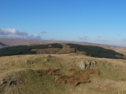 Matt on Castle Fell with tree covered Mabbin Crag behind